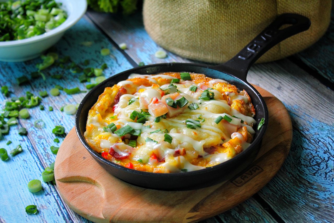 portfolio-img-01 Delicious frittata with cheese and vegetables in a rustic skillet, ideal for a hearty breakfast.