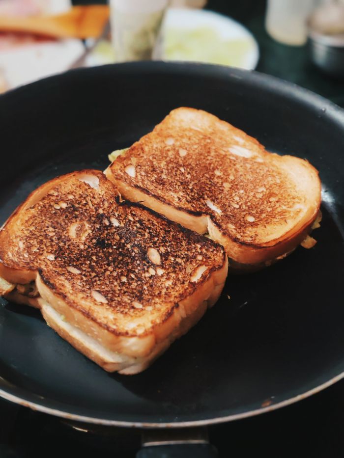 portfolio-img-04 Delicious grilled cheese sandwiches sizzling in a non-stick pan, ready to enjoy.