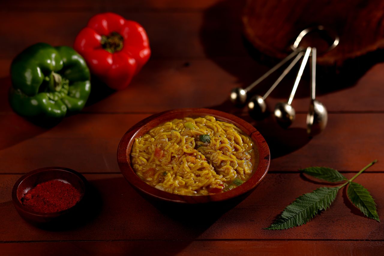 The Art of Drawing Readers In: Your attractive post title goes here Wooden table setting with instant noodles, colorful peppers, and spices, creating a cozy food scene.