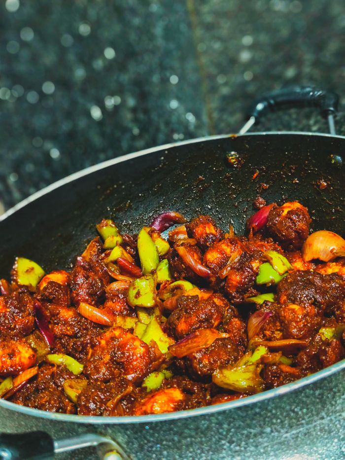 portfolio-img-05 Spicy chilli prawns cooked with vegetables in a traditional Indian wok, showcasing vibrant flavors and colors.